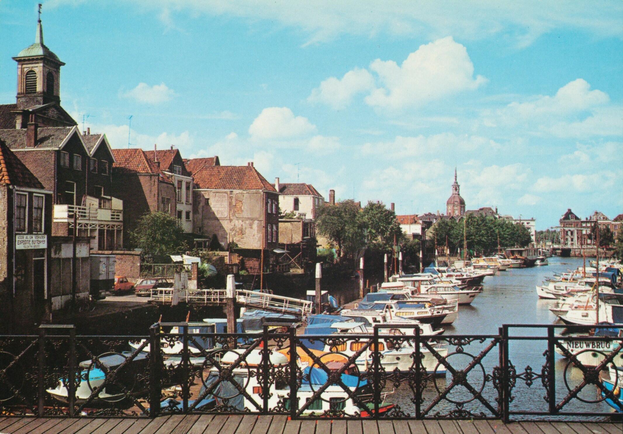 De foto uit de Beeldbank uit 1970 werd genomen vanaf de Nieuwbrug met in de achtergrond de Groothoofdspoort die Nesbitt van dichterbij vastlegde.